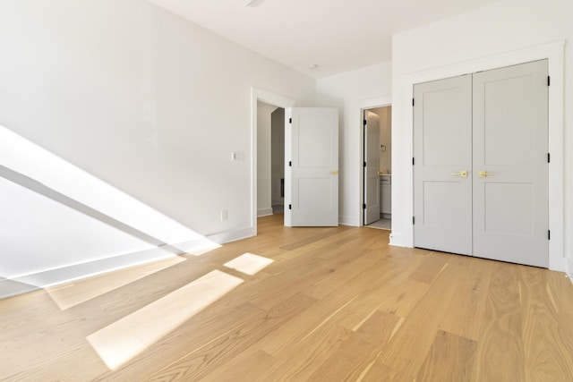 unfurnished bedroom with light wood-type flooring, baseboards, and a closet