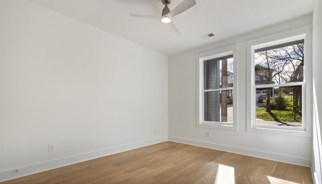 spare room featuring a healthy amount of sunlight, visible vents, light wood finished floors, and baseboards