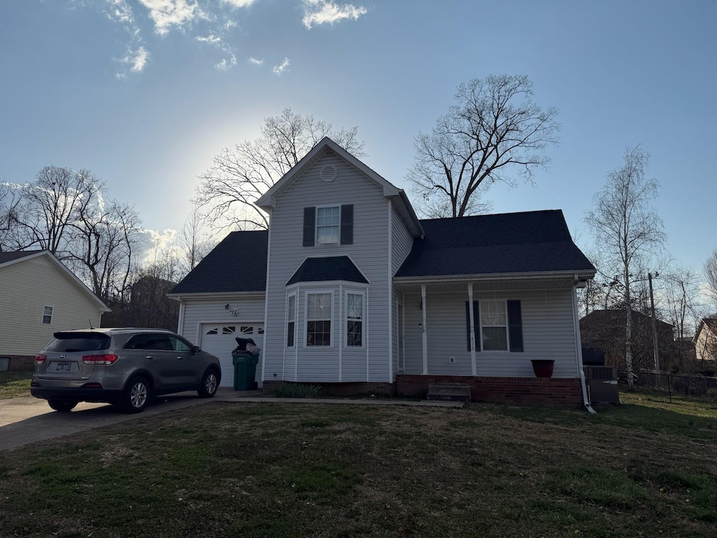 traditional-style house featuring a garage, a front yard, a porch, and concrete driveway