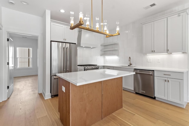 kitchen with visible vents, premium range hood, a sink, stainless steel appliances, and a center island