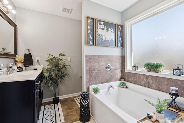 full bathroom with tile patterned floors, visible vents, a garden tub, baseboards, and vanity