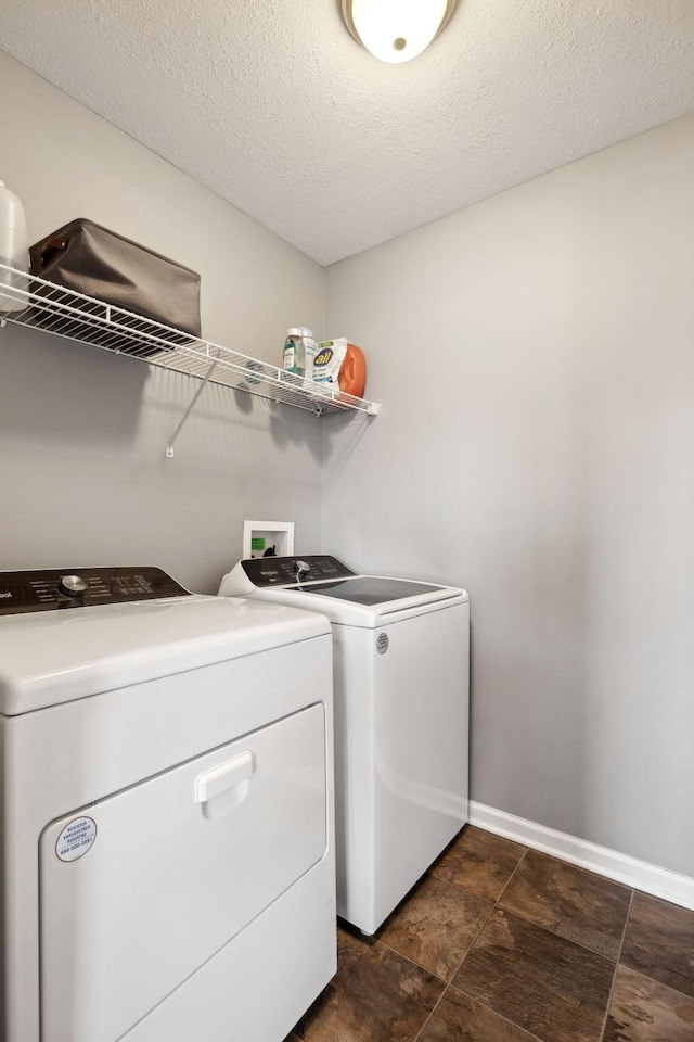 laundry area with laundry area, independent washer and dryer, a textured ceiling, and baseboards