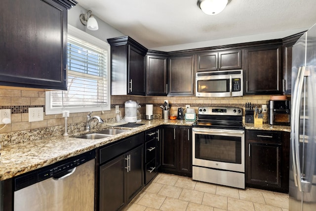 kitchen with a sink, decorative backsplash, light stone counters, and stainless steel appliances