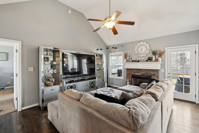 living area featuring baseboards, a stone fireplace, high vaulted ceiling, a ceiling fan, and dark wood-style flooring