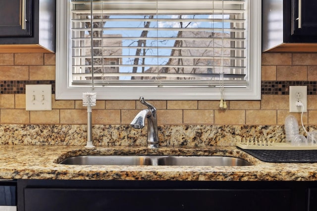 room details with decorative backsplash, light stone countertops, and a sink