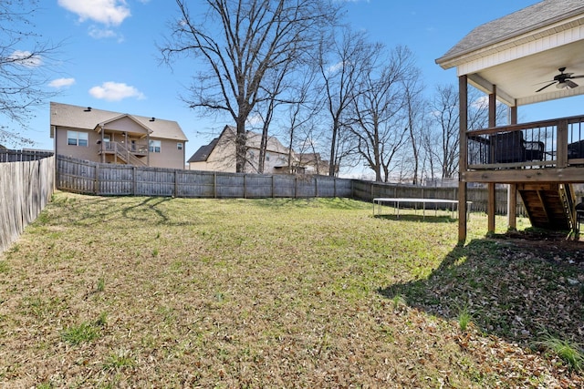 view of yard featuring a fenced backyard, a trampoline, ceiling fan, and stairs