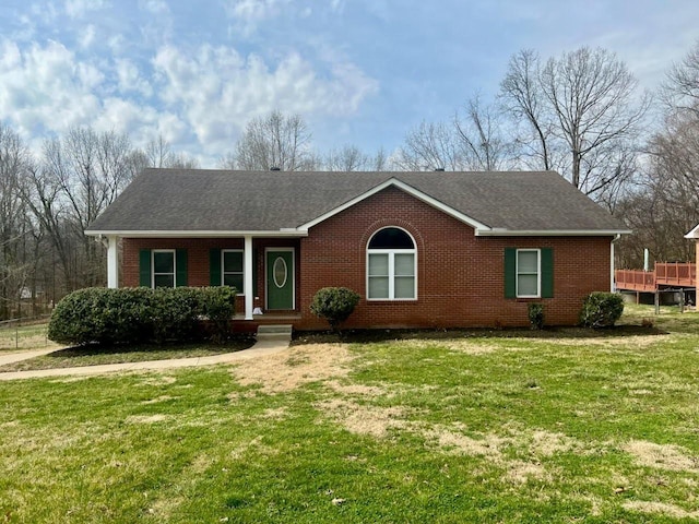 ranch-style home featuring brick siding, covered porch, a shingled roof, and a front lawn