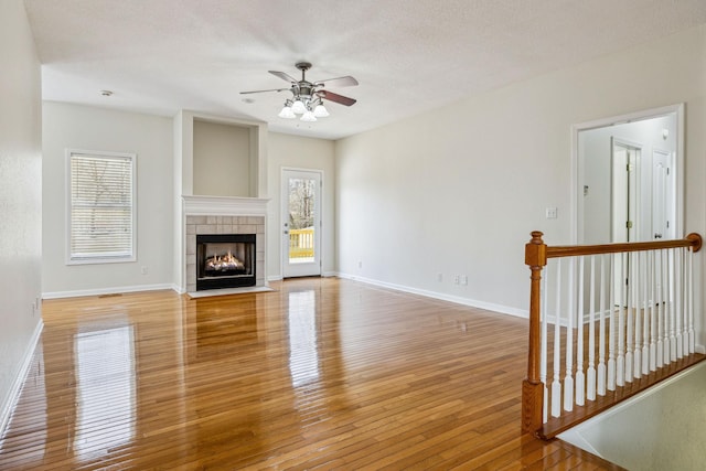334 Idaho Springs Rd, Clarksville, TN 37043 - unfurnished living room with baseboards, light wood-style flooring, a tile fireplace, ceiling fan, and a textured ceiling