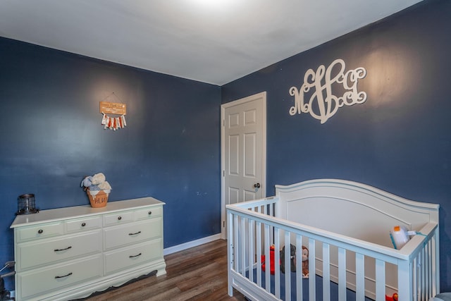 bedroom with dark wood-type flooring, a nursery area, and baseboards