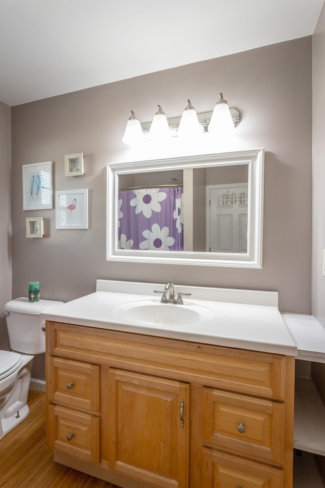 full bath with toilet, vanity, and wood finished floors