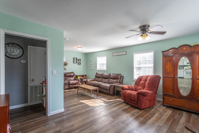 living room featuring visible vents, baseboards, dark wood-type flooring, and a ceiling fan