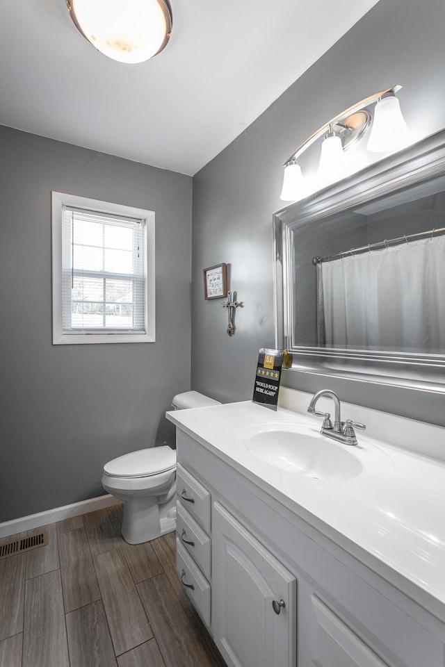 full bathroom with vanity, baseboards, visible vents, wood finish floors, and toilet