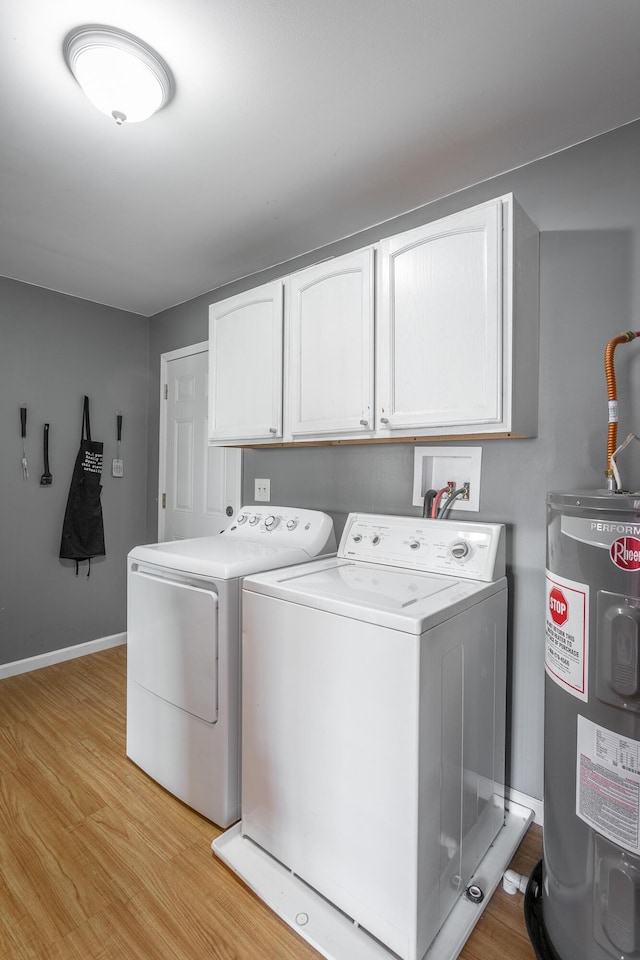 clothes washing area with baseboards, cabinet space, light wood-style floors, electric water heater, and washing machine and dryer