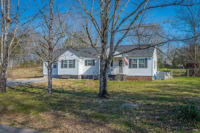 view of front facade with a front lawn, fence, a shingled roof, crawl space, and central AC unit