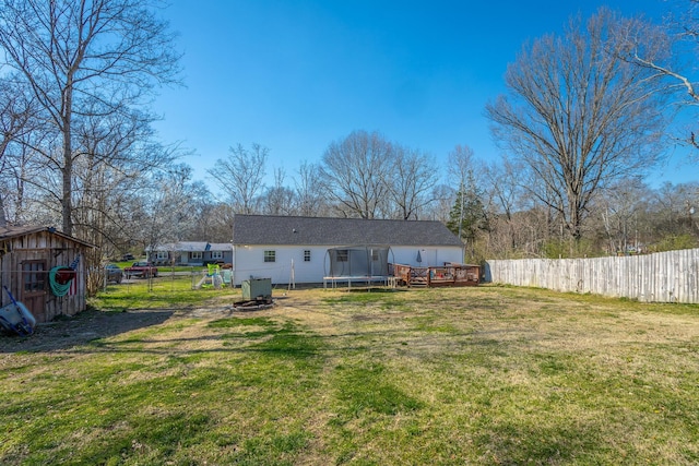 back of property featuring a lawn, a trampoline, a fenced backyard, a storage shed, and an outdoor structure