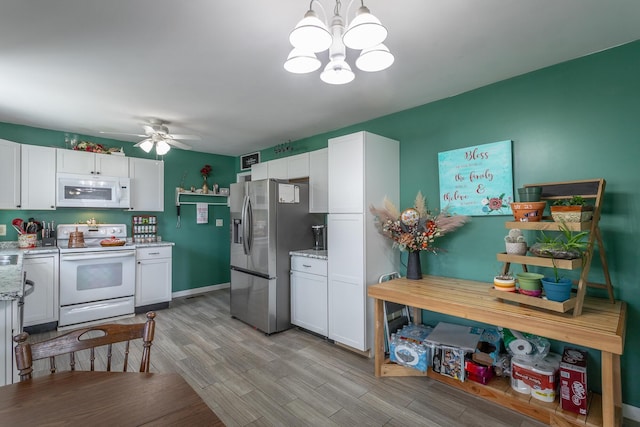 kitchen featuring white appliances, light stone counters, light wood finished floors, white cabinets, and ceiling fan with notable chandelier