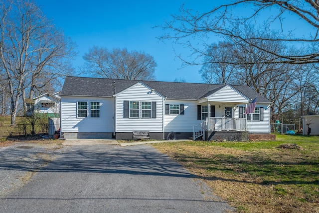 view of front of house featuring covered porch, a shingled roof, and a front yard