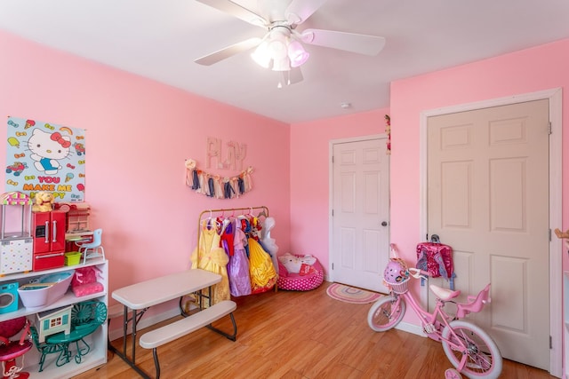 recreation room featuring baseboards, a ceiling fan, and wood finished floors