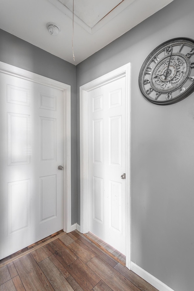 unfurnished bedroom with attic access, baseboards, and wood-type flooring