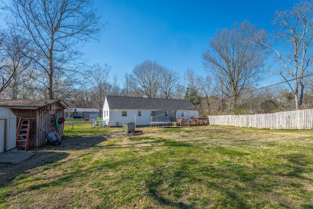 rear view of house with an outbuilding, fence private yard, a storage shed, a trampoline, and a lawn