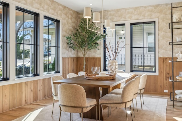 dining room featuring plenty of natural light, wooden walls, and wood finished floors