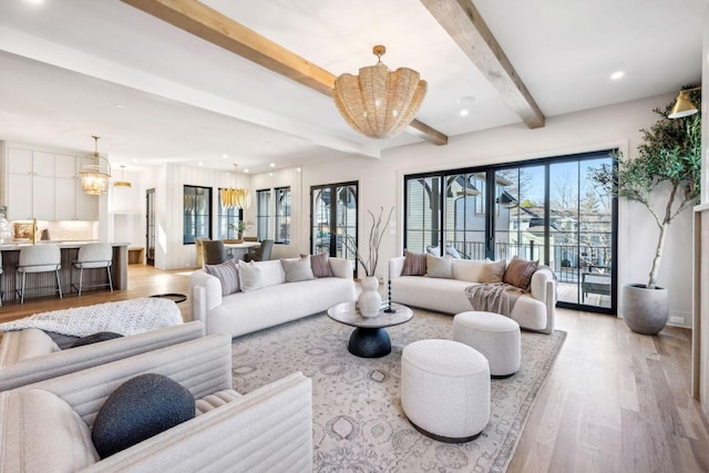 living area with a wealth of natural light, a notable chandelier, light wood finished floors, and beam ceiling