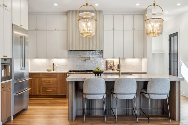 kitchen featuring brown cabinetry, stainless steel appliances, light wood-style floors, and tasteful backsplash