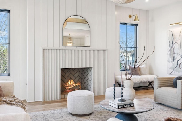 sitting room with a warm lit fireplace and wood finished floors