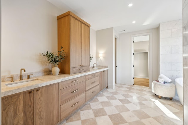 bathroom featuring a sink, a freestanding bath, double vanity, and tile patterned floors