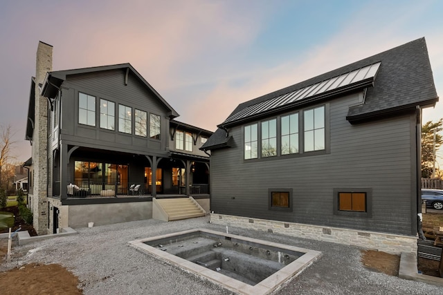 back of house with an in ground hot tub and a chimney