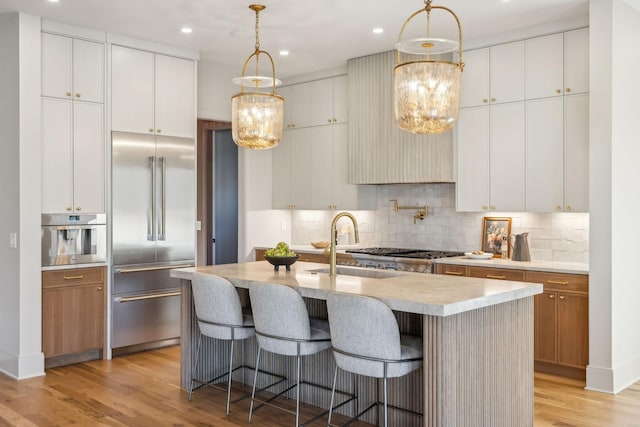 kitchen with light countertops, light wood-style flooring, a notable chandelier, and stainless steel appliances