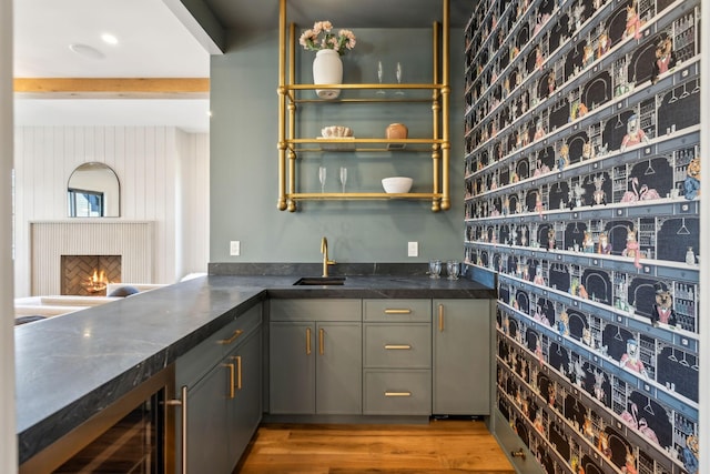 bar with wood finished floors, brick wall, wet bar, a sink, and wine cooler