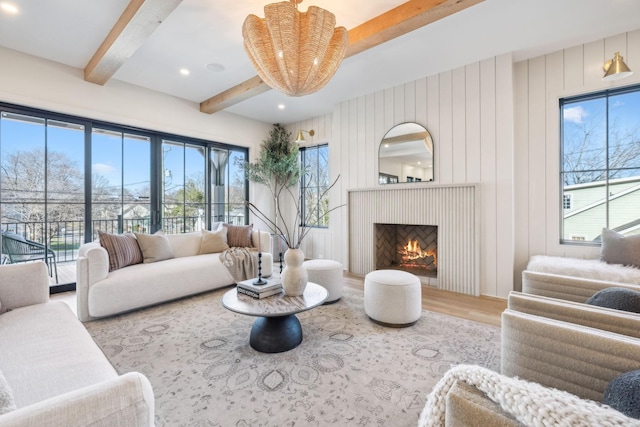 living area with beam ceiling, a warm lit fireplace, and wood finished floors