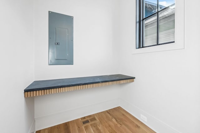 room details featuring electric panel, visible vents, baseboards, and wood finished floors