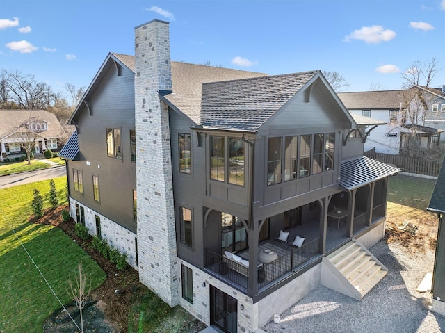 exterior space featuring a lawn, a chimney, roof with shingles, and a sunroom