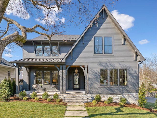 view of front of home featuring covered porch, a front lawn, and a standing seam roof