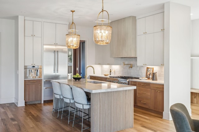 kitchen featuring light wood finished floors, tasteful backsplash, a breakfast bar area, appliances with stainless steel finishes, and a sink