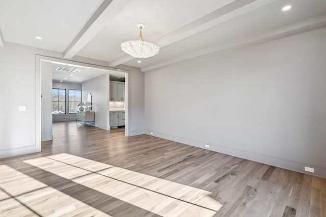 unfurnished room with visible vents, baseboards, beam ceiling, light wood-style flooring, and an inviting chandelier