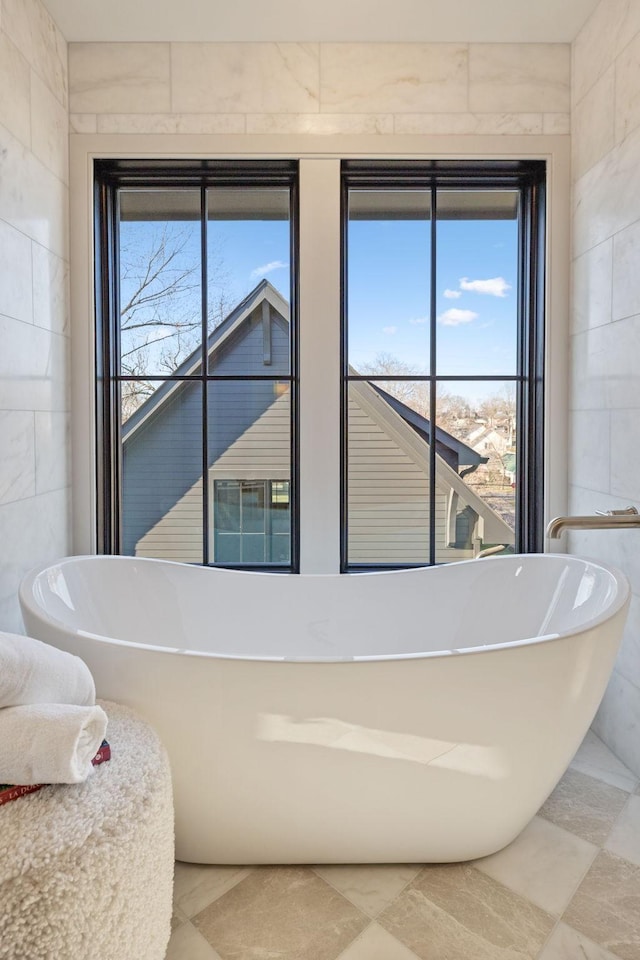 full bath featuring a soaking tub, plenty of natural light, and tile walls