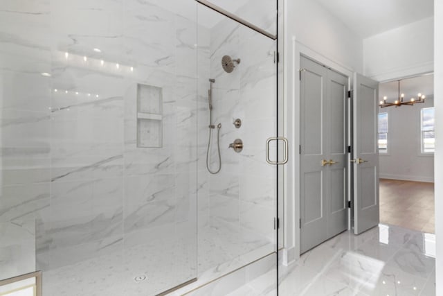 full bath with a marble finish shower, a notable chandelier, and marble finish floor