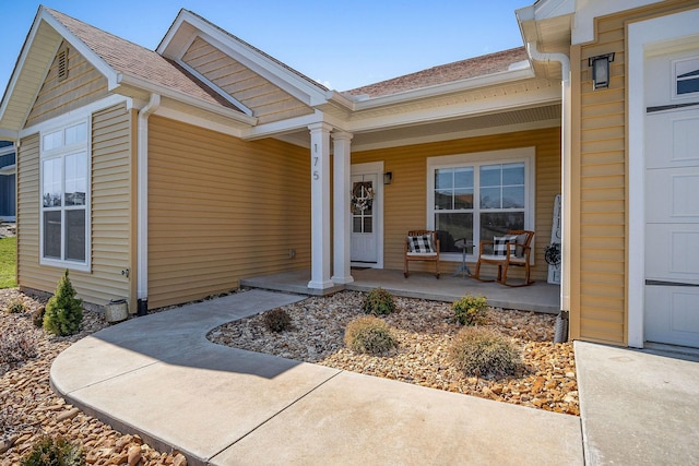 property entrance with covered porch, an attached garage, and a shingled roof