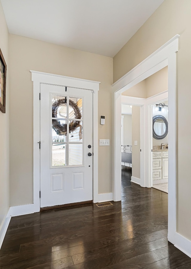 entryway with visible vents, dark wood-type flooring, and baseboards