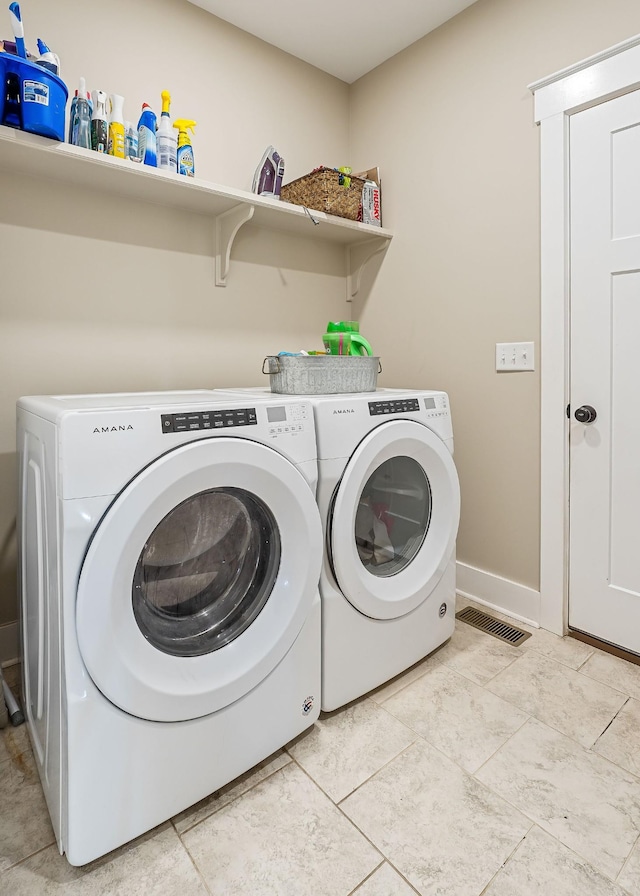 laundry room with light tile patterned floors, visible vents, baseboards, laundry area, and separate washer and dryer