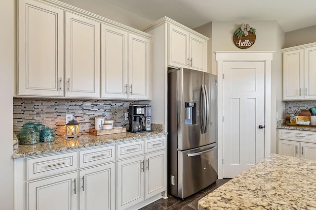 kitchen featuring dark wood-style floors, light stone counters, stainless steel fridge with ice dispenser, and backsplash