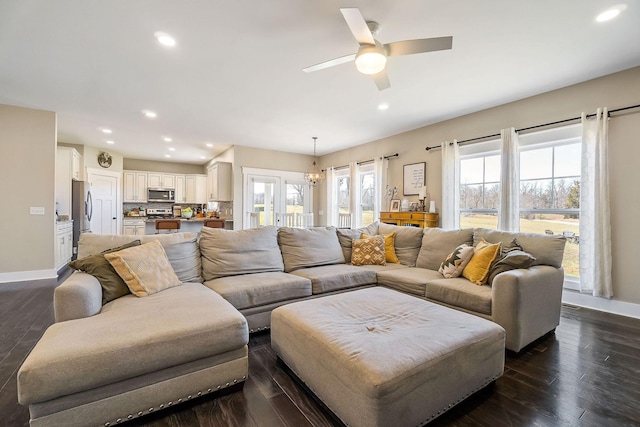 living room with recessed lighting, ceiling fan with notable chandelier, baseboards, and dark wood-style flooring