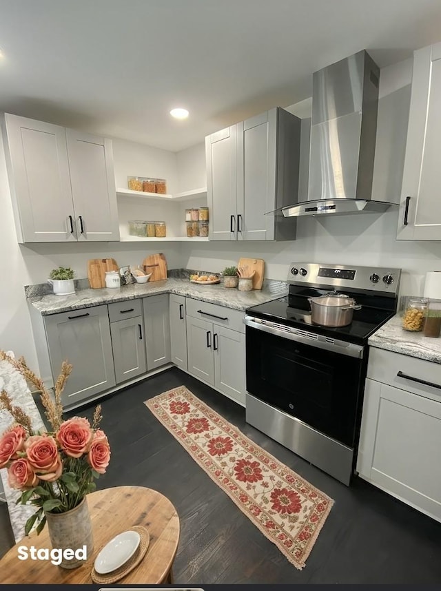 kitchen featuring dark wood-type flooring, recessed lighting, stainless steel range with electric stovetop, wall chimney exhaust hood, and open shelves