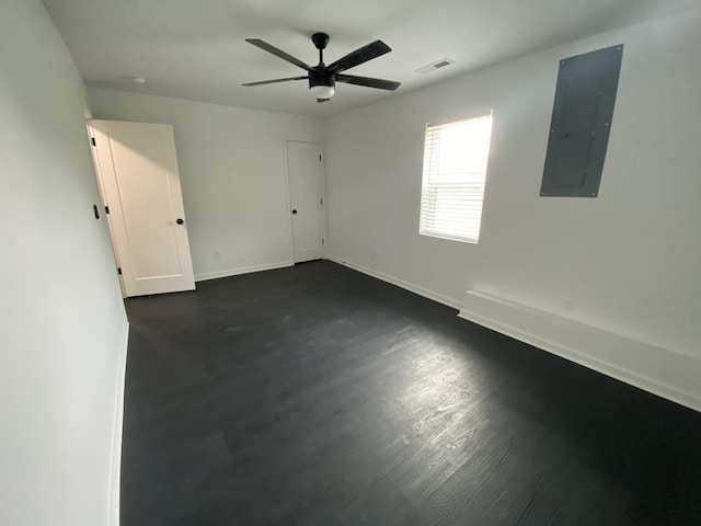 empty room with visible vents, ceiling fan, baseboards, dark wood finished floors, and electric panel