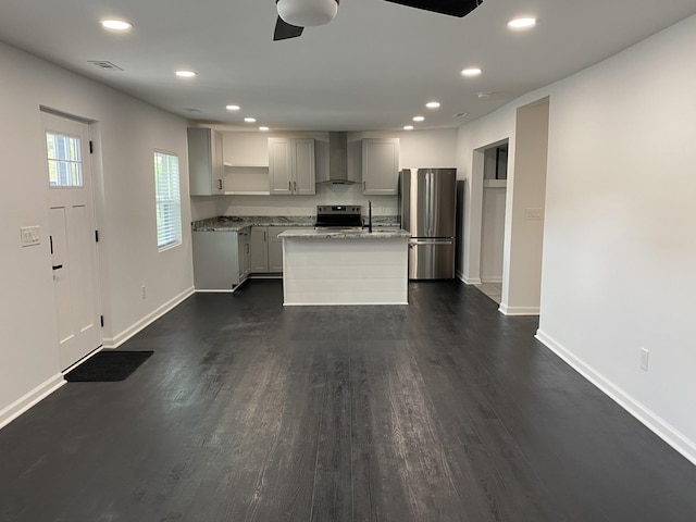 kitchen featuring visible vents, an island with sink, appliances with stainless steel finishes, dark wood-style floors, and wall chimney exhaust hood