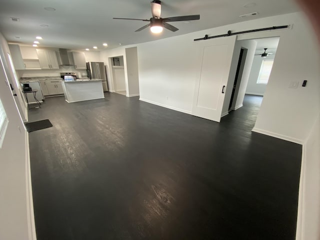 unfurnished living room featuring visible vents, recessed lighting, a barn door, baseboards, and ceiling fan