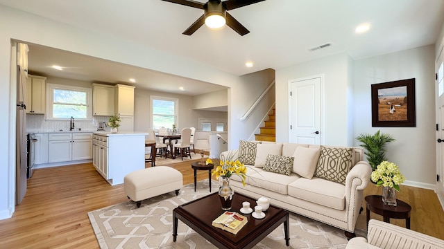 living area featuring stairway, visible vents, recessed lighting, ceiling fan, and light wood-type flooring